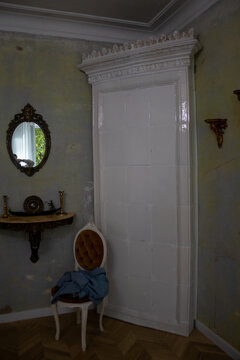 Classic room interior with white glazed tile stove mirror and chair