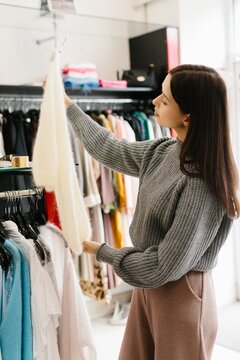 Young woman choosing sweater while shopping at a boutique