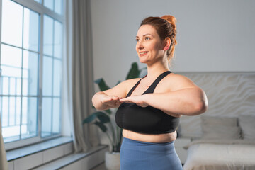 Fototapeta premium Fitness workout training. Woman practicing fitness at home. Plus size female doing sports exercise at home indoor. Girl in sportswear have workout weight training for weight loss. Sport and fitness