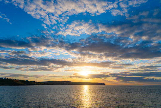Golden sunset over the North Sea near Whitby, with sunlight reflecting across the water beneath an expansive and dramatic evening sky.