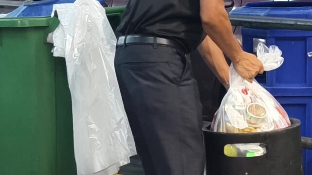 Shopping mall cleaning staff changing the trash bag and managing waste disposal.