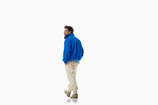 Fashionable man stands in bright blue sweater and relaxed cream pants. Concept of color block menswear, casual style, comfort, individuality and modern wardrobe.