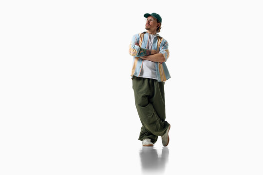 Man crosses arms in striped shirt and oversized green trousers. Concept of confident personal style, relaxed menswear, contemporary fashion and individuality.