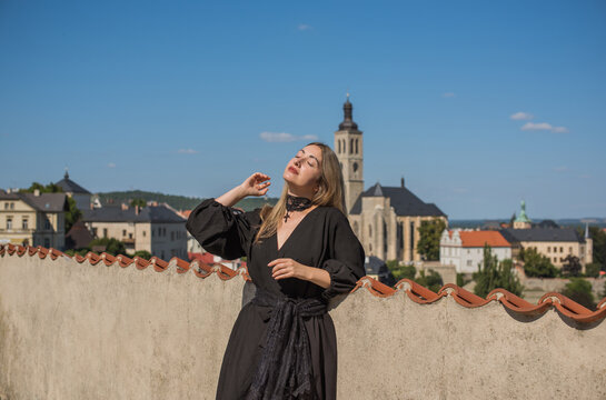 Woman exploring historic streets of Kutna Hora with St. Barbara Cathedral in background, Czech Republic travel concept