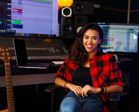 Portrait of a young smiling woman sitting in a recording studio and looking at camera