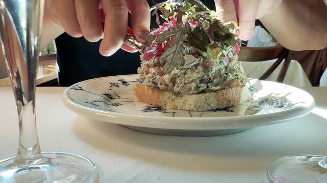 Person Eating Traditional Danish Smorrebrod at a Restaurant