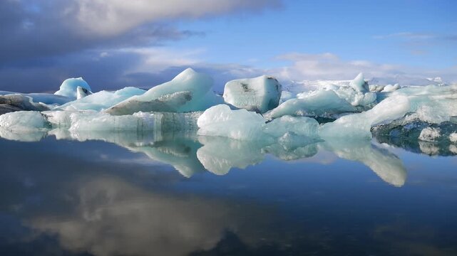 Stunning blue icebergs from the Vatnajokull glacier floating in the calm, reflective water of the Jokulsarlon glacial lagoon in Iceland