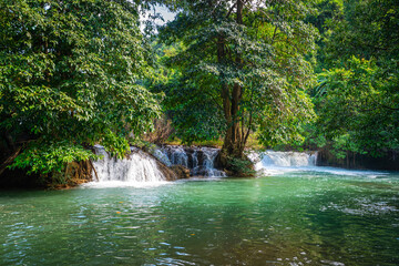 Clear emerald stream flowing over small natural rock cascades surrounded by dense green forest foliage at Glue-Thor Waterfall (Kyone Htaw Waterfall), Kayin State, Myanmar. © Around Ball