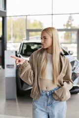 Fototapeta premium Woman pointing finger in car dealership