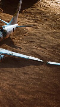 A large airplane sits abandoned on the ground in a remote area. The plane shows signs of wear and neglect. The surrounding ground is brown and flat, with no other objects nearby.