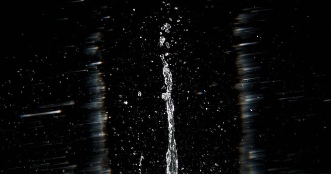 Experience captivating footage of small water droplets splashing from a heavy objects impact, all set against a rich black background, ideal for enhancing motion graphics and stunning visual effects