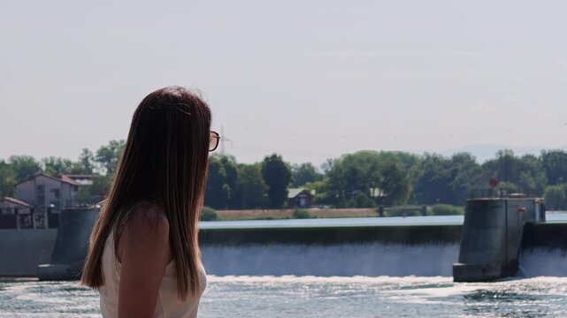 Woman with long hair looking at Breisach agricultural dam on the Rhine River, on the border between Germany and France