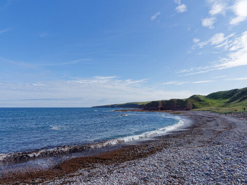 Looking East from New Aberdour Beach down the steeply shelving shingle beach with quantities of Seaweed being brought in with the Tide.