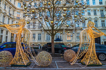Naklejka premium Luxury hotel courtyard decorated for Christmas holidays with illuminated angel light installations and decorated tree in Karlovy Vary, Czech Republic