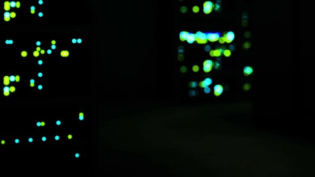 The scene shows various servers located in a data center at night. Bright lights blink in different colors, indicating data activity. The background is dark and focused on the servers.