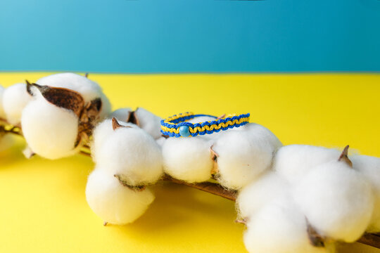 Blue yellow macrame bracelet with bead. Wristband in national Ukrainian flag colors with cotton flower on background. Copy space