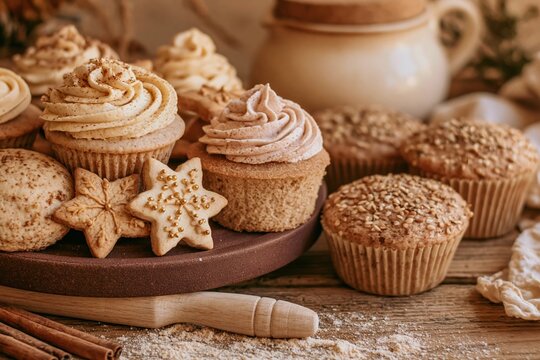 Assorted frosted cupcakes, star cookies and muffins on a dark wooden board, featuring creamy buttercream textures for home baking marketing