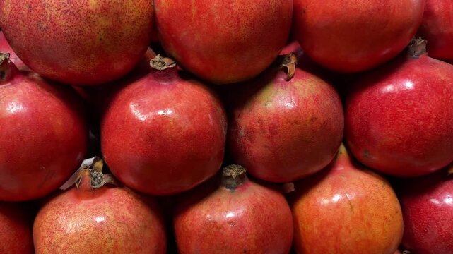 Rows of glossy fresh pomegranate fruit stacked on market display in close up pattern