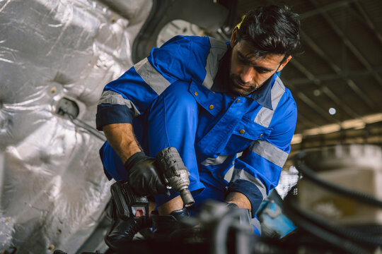 Hispanic Latin Indian Male Mechanic Repairing Truck Engine In Auto Service Garage Workshop.