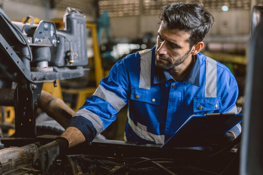 Hispanic Latin Indian Male Mechanic Repairing Truck Engine In Auto Service Garage Workshop.