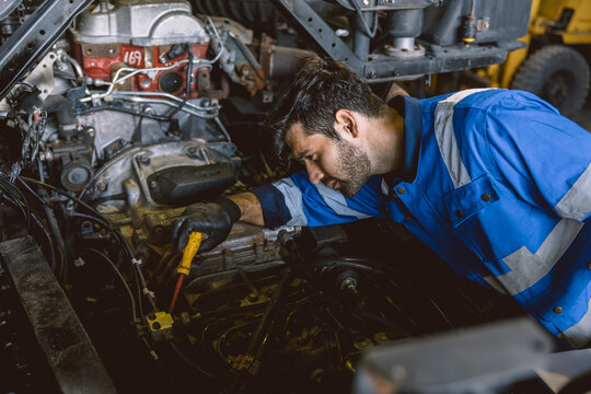 Hispanic Latin Indian Male Mechanic Repairing Truck Engine In Auto Service Garage Workshop.
