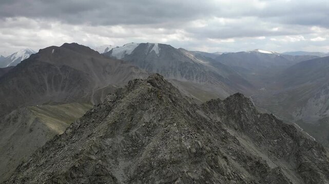 A panoramic aerial view of the summit of Big Almaty Peak (3,680 m). A majestic mountain landscape with snow-capped four-thousanders in the background