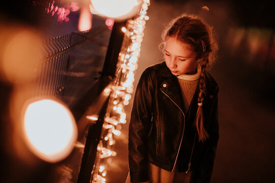 Thoughtful girl standing near glowing holiday decoration at night