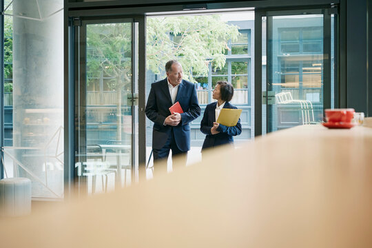 Businessman and businesswoman walk into a coffee shop