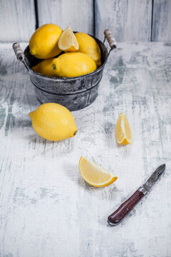 Bowl of lemon, lemon, sliced lemon and knife on wooden table
