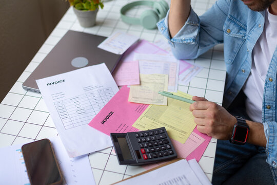 Calculating expenses with invoices and paperwork at home office desk