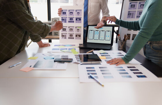 UX designers collaborating on mobile app wireframes and user interface concepts, planning digital product development for a startup project