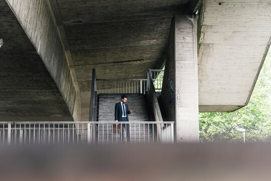 Businessman at underpass checking cell phone