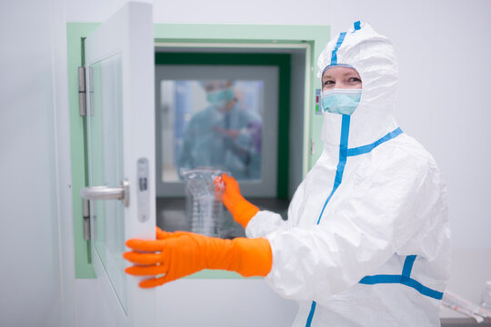 Lab technician wearing cleanroom overall at material sluice