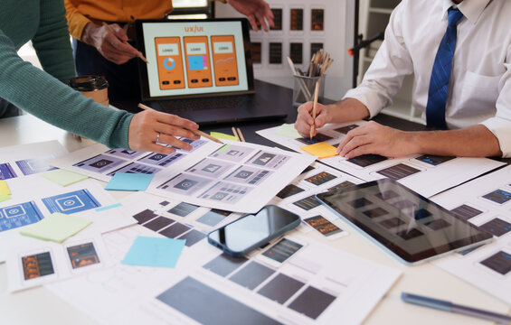UX UI designers collaborating on web and mobile application prototypes, brainstorming, and planning interface layouts for new digital product development