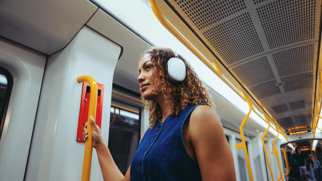 Woman wearing headphones travels by metro on city commute