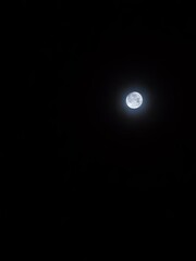 Bright full moon glowing in the center of dark night sky. © Vitchapon
