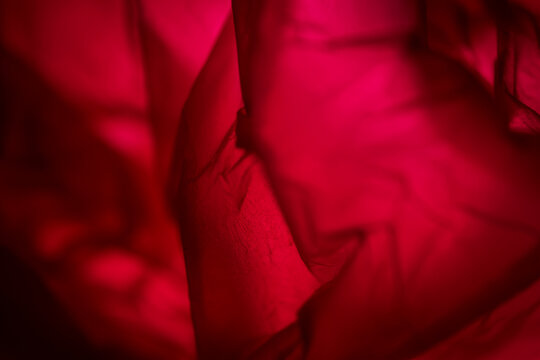 Extreme close up of red plastic texture background. The plastic surface is wrinkly and tattered making abstract pattern. Selective focus, shallow depth of field.