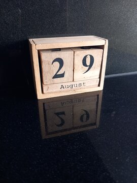 Wooden Calendar Showing August 29 Date on Dark Reflective Surface