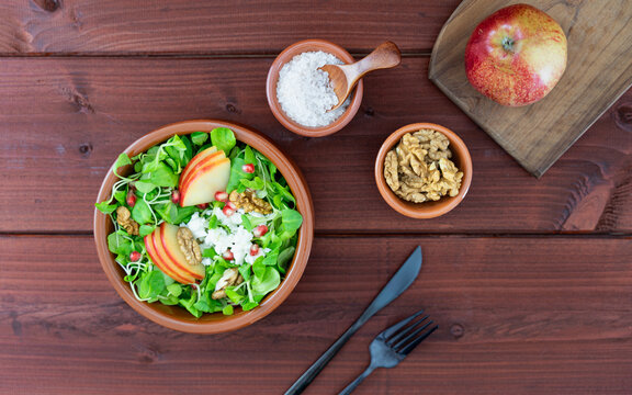 Apple and Lamb's Lettuce Salad on Rustic Wooden Table. Healthy salad bowl with lamb's lettuce, apple slices, walnuts and feta cheese served on a wooden background