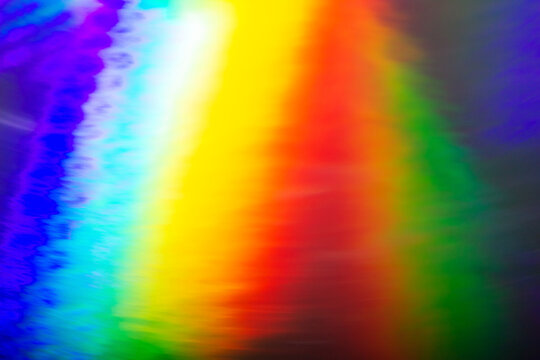 De focused abstract vibrant iridescent holographic rainbow foil background with light leaks. Glitter surface. Abstract blurred rainbow background.