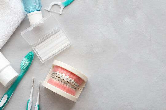 Various dental hygiene items like toothpaste, floss, toothbrush, and retainer are laid out on a light gray surface.