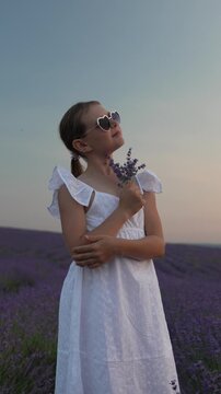 Lavender field elegance captured as a young girl in a white sundress enjoys the gentle breeze at twilight. Medium close up shot.