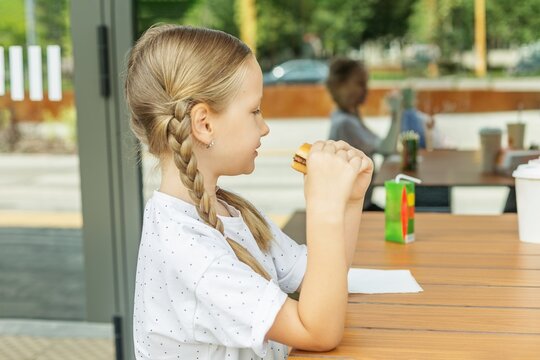 Child Eating Burger at Outdoor Restaurant Table