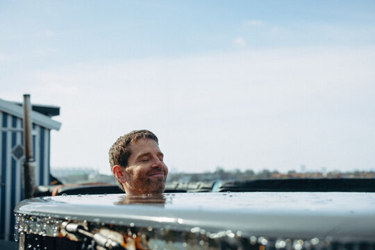 An outdoor recovery scene features a man submerged in ice bath water.
