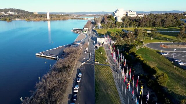 Drone aerial landscape of international flag displays and promenade foreshore pathway along the Lake Burley Griffin waterfront Parliamentary Triangle in Parkes Canberra ACT Australia tourism travel