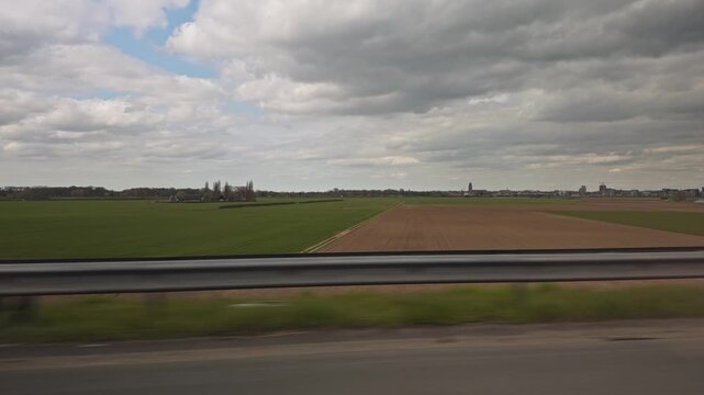 View from a car driving on the A1 highway past fields with the skyline of Deventer in background