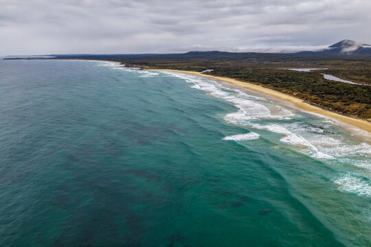Aerial view of Lake Arragan Beach and the surrounding coastal landscape, featuring a long sandy shoreline, Pacific Ocean, native bushland and pristine natural scenery within Yuraygir National Park 