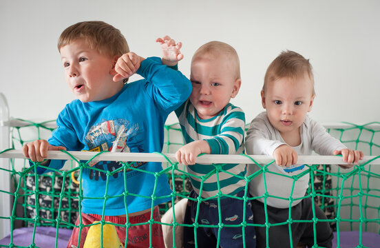Big brother leads twin babies in an indoor adventure in the crib