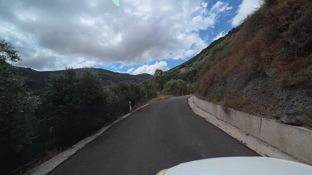 A car drives slowly along a dangerous winding mountain road on the island of Crete, Greece.