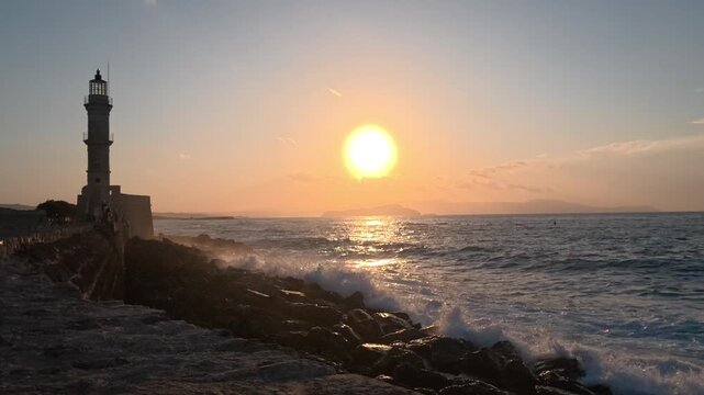 Silhouette of lighthouse in sea at sunset in the city of Chania, island of Crete, Greece. Beautiful seascape at sunset